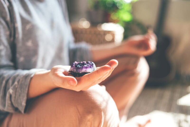 A woman meditating with a crystal in her hand