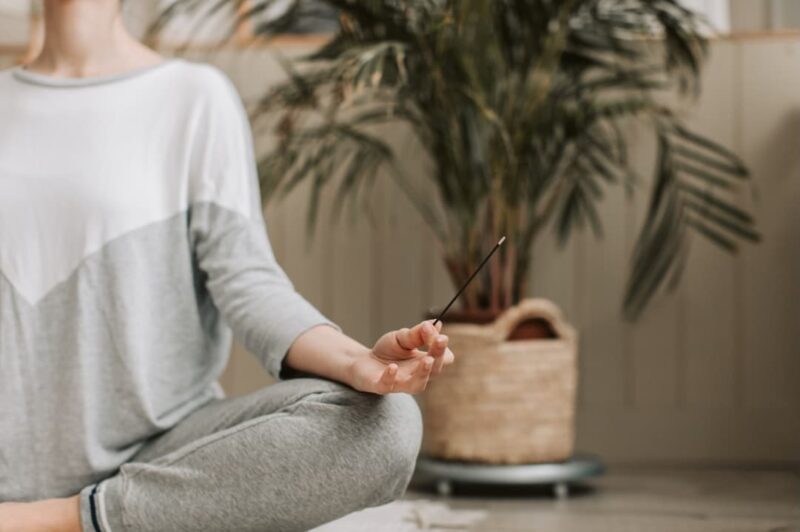 A serene woman meditating with an incense stick for cleansing.