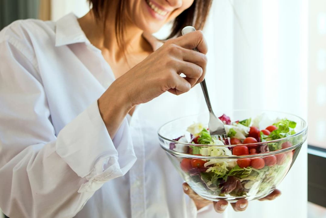 person holding a salad bowl filled with salad and radishes